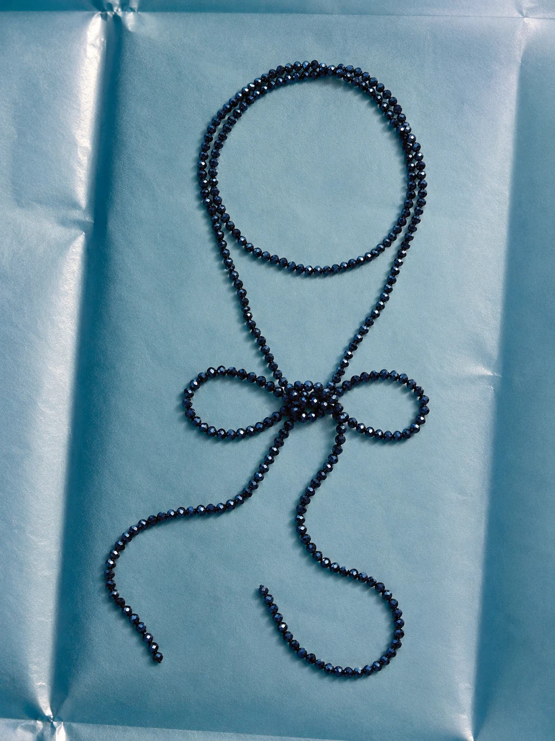 Collana di perline blu su carta azzurra